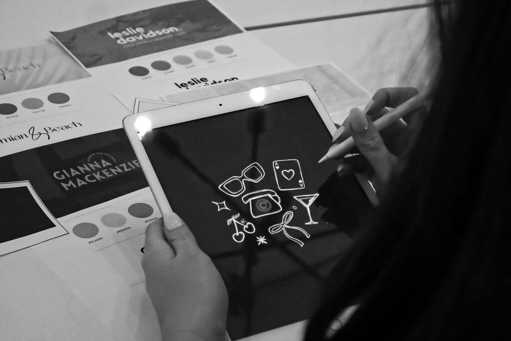 Woman Drawing Icons on a Tablet with Brand Guidelines in the Background
